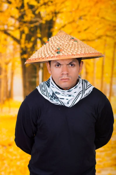 秋のバック グラウンドで彼の背中に腕を持つアジアの円錐形の帽子を着ているハンサムなヒスパニック系の若いビジネス男の肖像 — ストック写真