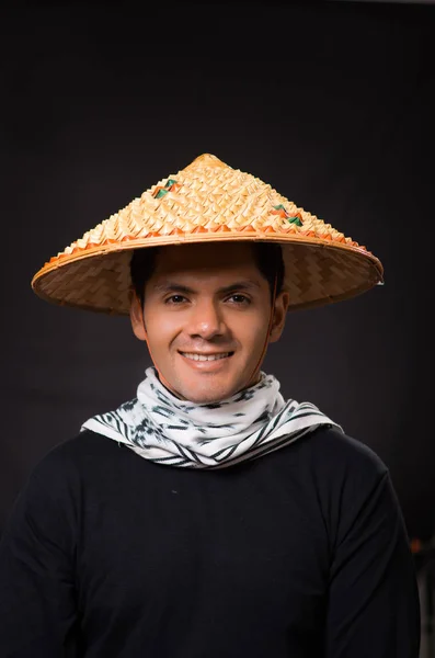Retrato de un joven hombre de negocios hispano guapo con un sombrero cónico asiático en fondo negro — Foto de Stock