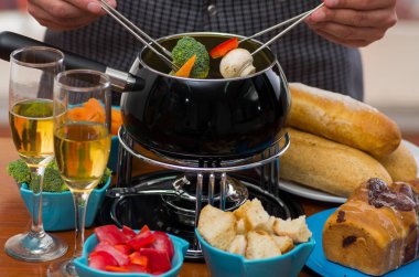 Bir parça ekmek, brokoli ve kırmızı biber ile peynir kaplı daldırma bir çatal ile tutan adam gurme İsviçre fondü yemek çeşitli peynir ve peynir fondü, ısıtmalı bir pot ile kapatın ve