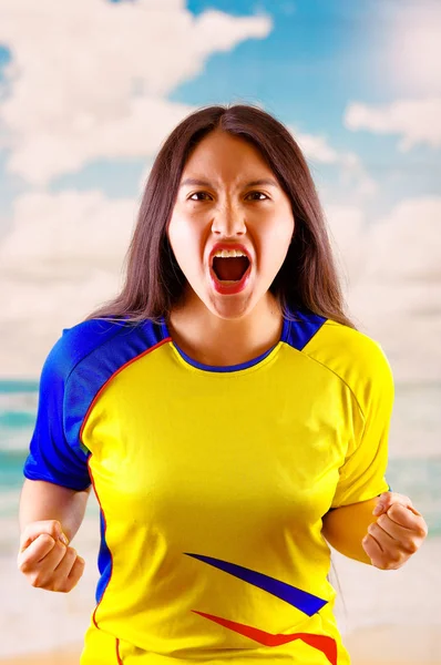 Młoda kobieta ekwadorski sobie oficjalny maraton piłki nożnej koszuli stojący stoi aparat, bardzo zaangażowaną język ciała oglądanie gry z wielkim entuzjazmem, Błękitne niebo i chmury tło — Zdjęcie stockowe