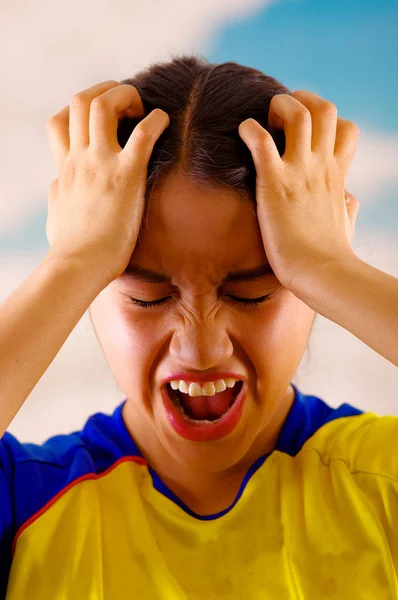 Jeune femme écuadorienne portant une chemise officielle de football Marathon debout face à la caméra, un langage corporel très engagé regardant le jeu avec beaucoup d'enthousiasme, un ciel bleu et un fond nuageux — Photo