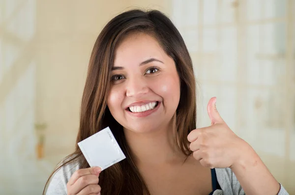 Junge schöne Ärztin hält ein Kondompaket und macht mit der Hand einen Daumen nach oben, Safe-Sex-Konzept. Schutz vor Aids und Geburtenkontrolle — Stockfoto