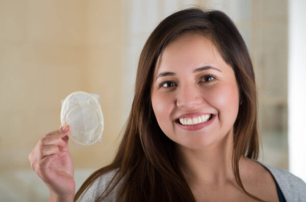 Young beautiful girl holding an open female condom, safe sex concept. Protection against AIDS and birth control