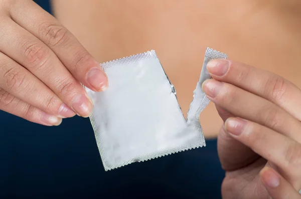 Close up of a woman opening a male condom package, signal with her hand, safe sex concept. Protection against AIDS and birth control — Stock Photo, Image