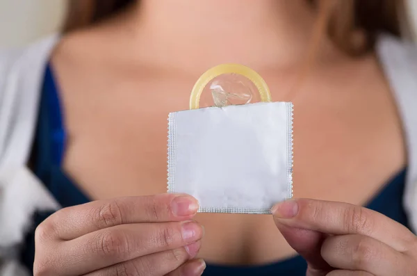 Close up de uma jovem segurando um pacote de preservativo aberto, para prevenção de aids e controle de natalidade — Fotografia de Stock