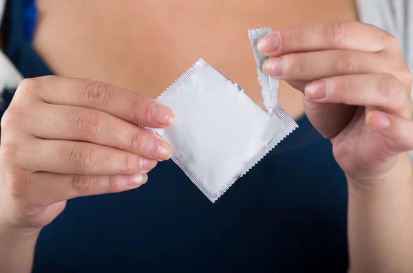 Primer plano de una mujer abriendo un paquete de preservativos masculinos, señal con su mano, concepto de sexo seguro. Protección contra el SIDA y anticonceptivos — Foto de Stock