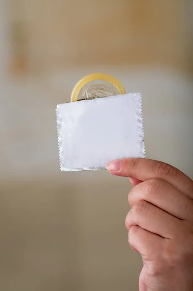 Close up de uma jovem segurando um pacote de preservativo aberto, para prevenção de aids e controle de natalidade — Fotografia de Stock