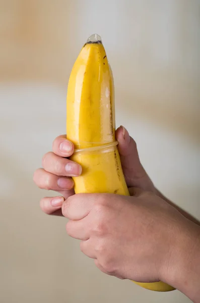 Condón masculino que cubre un plátano, sexo seguro, plan familiar, prevención de enfermedades de transmisión sexual — Foto de Stock