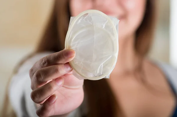 Close up of a young beautiful girl holding an open female condom, safe sex concept. Protection against AIDS and birth control — Stock Photo, Image