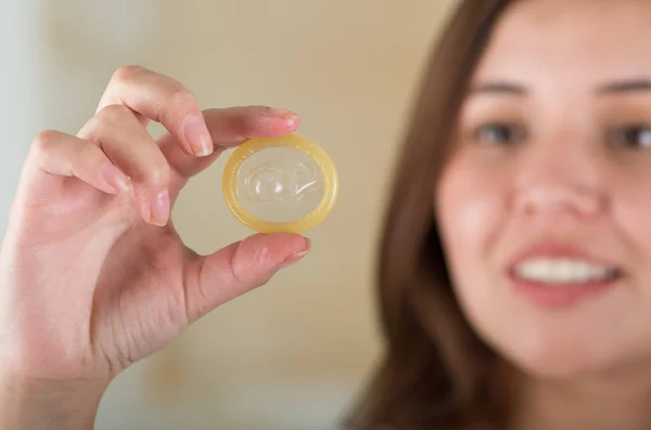 Close up of a beautiful young woman holding an open condom for aids prevention and birth control — Stock Photo, Image