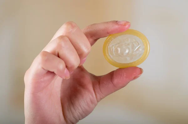 Närbild på en hand som håller en öppen kondom för aids förebyggande och födelsekontroll — Stockfoto
