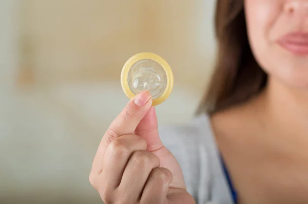 Primer plano de una hermosa joven sosteniendo un condón abierto para la prevención del SIDA y el control de la natalidad — Foto de Stock
