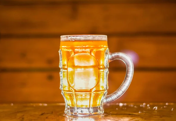 Närbild av en blond hantverksöl som fyllt i en pint glas på trä bakgrund — Stockfoto