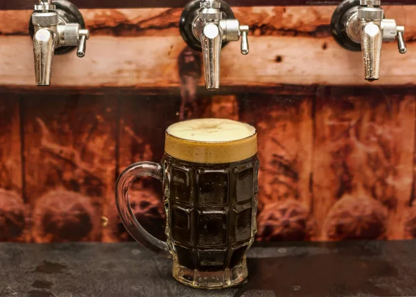 Deliciosa cerveja artesanal escura preenchida em um copo de cerveja na mesa de madeira — Fotografia de Stock