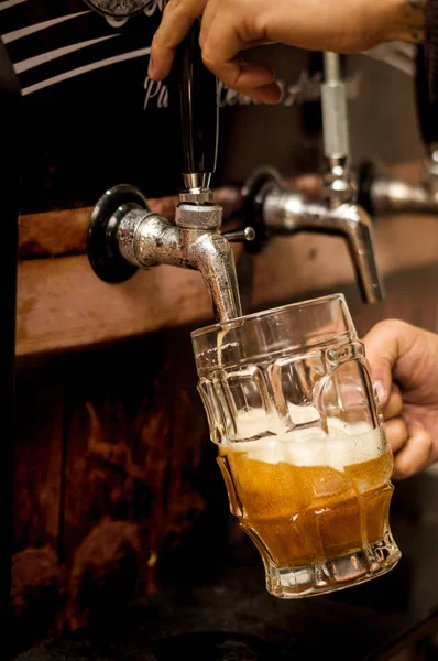 Bartender filling up with craft beer a pint glass