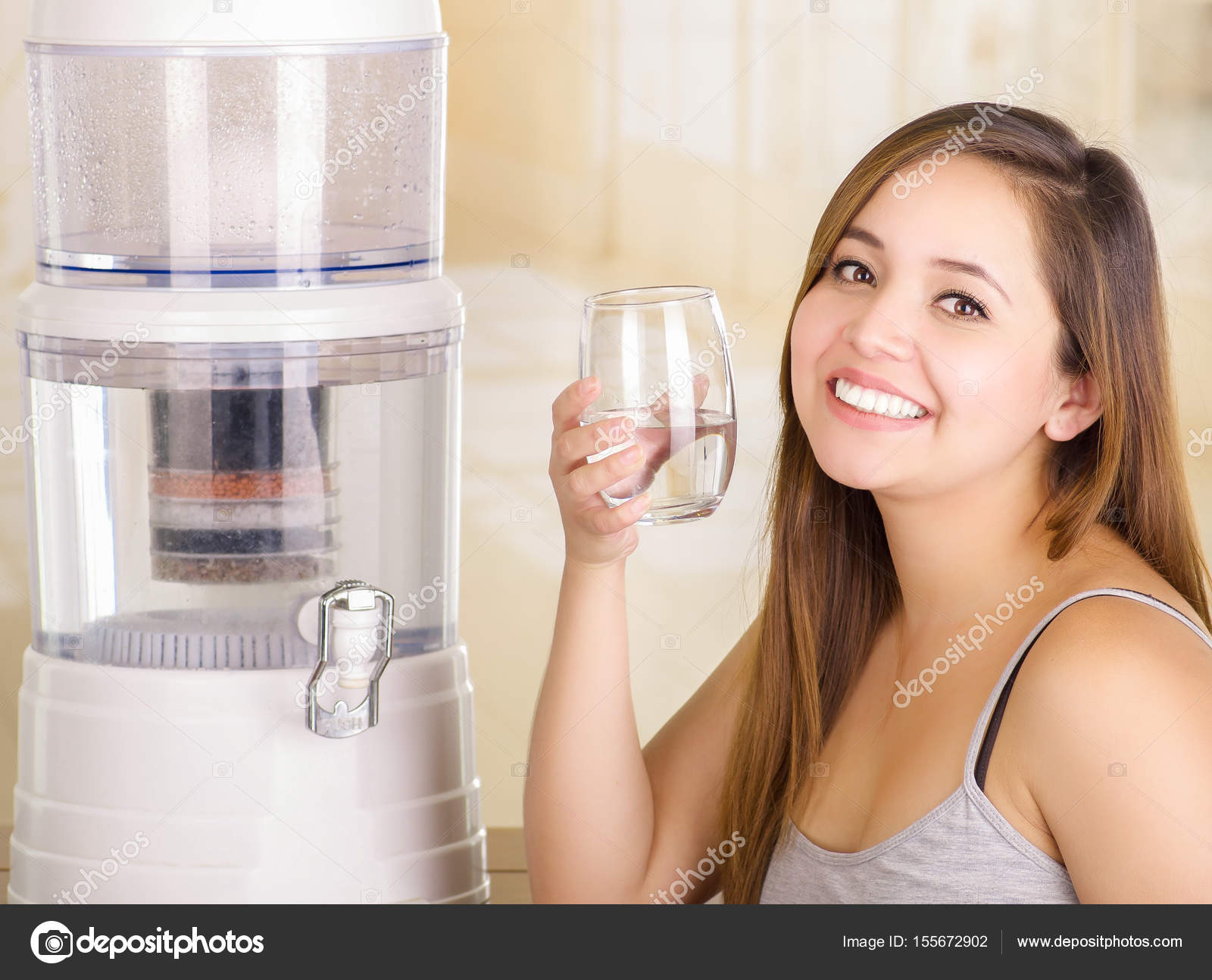 Beautiful smiling woman holding a glass of water, with a filter system of water  purifier on a kitchen background Stock Photo by ©pxhidalgo 155672902