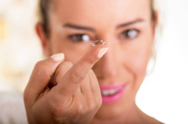 Kontakt lens üstünde parmak beyaz arka plan., görme ve eyecare kavramı yüzünde önünde tutan genç kadın