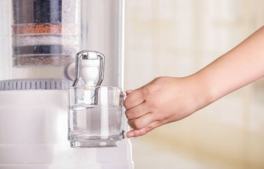 Bir bardak su, su temizleyici mutfak arka plan üzerinde bir filtre sistemi ile doldurma bir kadının yakın çekim