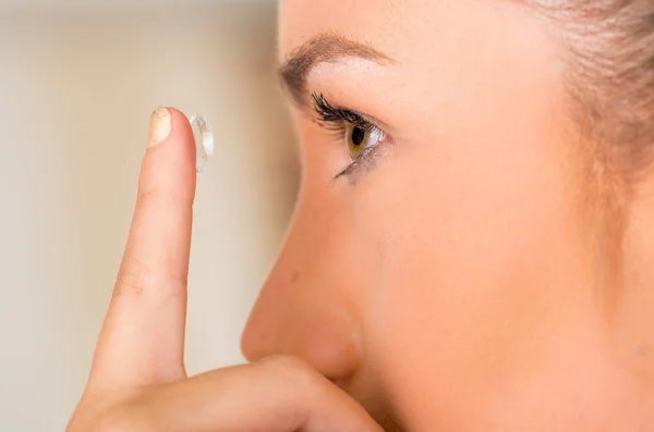 Young woman putting contact lens in her eye close up — Stock Photo, Image