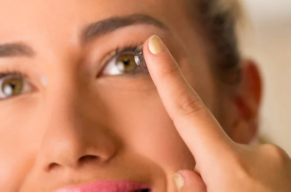 Young woman putting contact lens in her eye close up — Stock Photo, Image