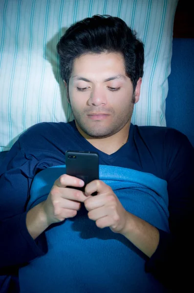 ベッドの上の男性は、寝ていないのでソーシャルメディアアディクト プレイ ビューの上のスマート フォン — ストック写真