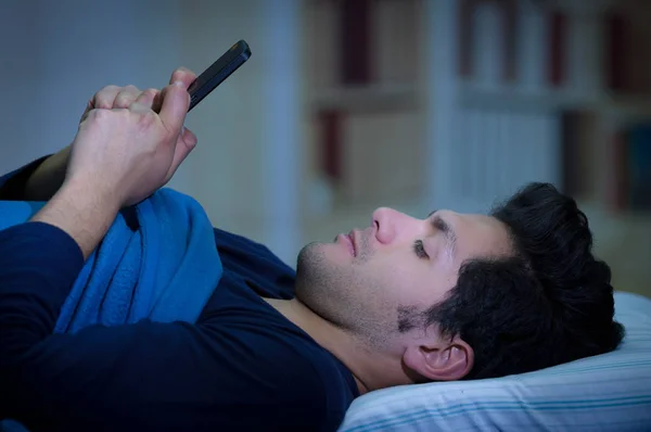 Media społecznościowe-addict mężczyzn na łóżku nie spać, bo grać inteligentny telefon, tło pokoju — Zdjęcie stockowe