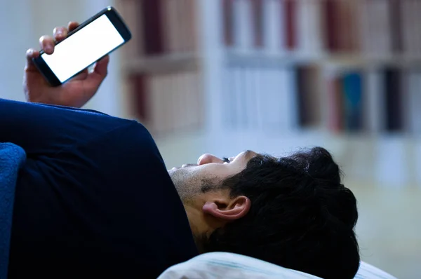 Les hommes toxicomanes des médias sociaux sur le lit ne dorment pas parce que jouer téléphone intelligent, fond de la chambre — Photo