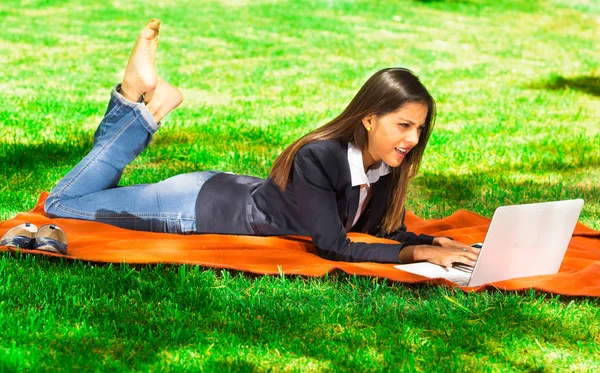 Giovane e felice ragazza utilizzando il suo computer portatile nel parco — Foto Stock