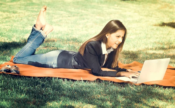 Ragazza giovane e felice utilizzando il suo computer portatile nel parco, effetto vintage — Foto Stock