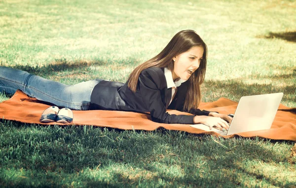 Chica joven y feliz con ordenador portátil en el parque, efecto vintage — Foto de Stock