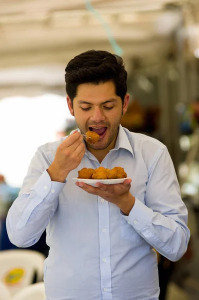 Close up of a handsome young man eating a homemade fritters with sugar and its ingredients — Stock Photo, Image