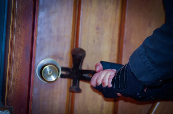 Close up of a burglar with crowbar trying break the door to enter the house — Stock Photo, Image