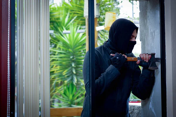 Inbrottstjuv med kofot försöker bryta fönstret för att gå in i huset — Stockfoto