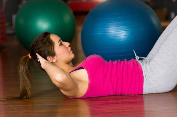 Beautiful woman doing abs in the gym on wooden floor — Stock Photo, Image