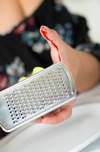 El primer plano de una mano de mujer se lesionó el dedo usando una rejilla en el plato de la cocina —  Fotos de Stock