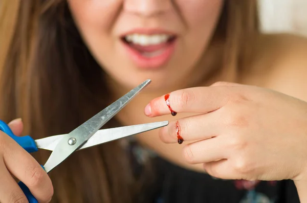 Młoda dziewczyna poniesionej cięcia palec nożyczkami — Zdjęcie stockowe