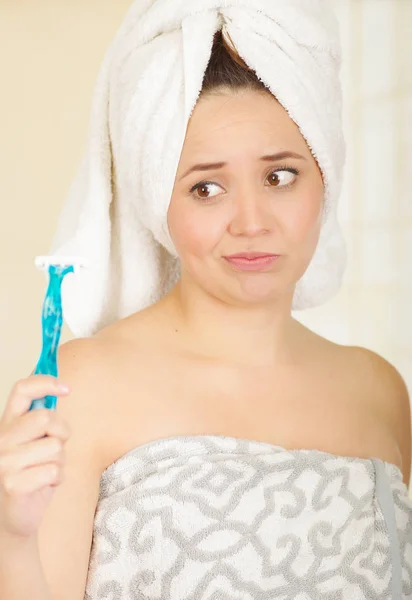 Bella fresca ragazza infelice con dopo asciugamano doccia tenendo rasoio blu — Foto Stock