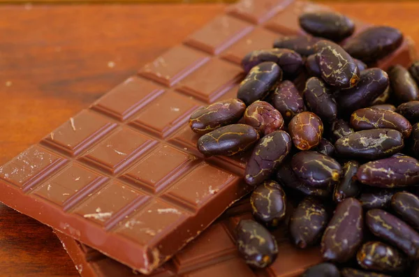 Cocoa beans and chocoalte bar on natural wooden table — Stock Photo, Image