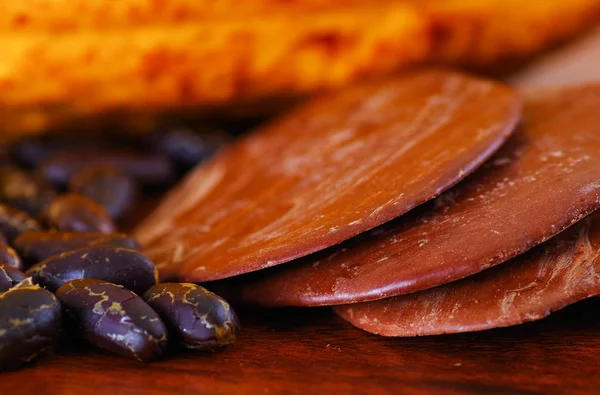 Primer plano de un grano de cacao seco oscuro con algunos trozos de chocolate negro sobre un fondo de madera —  Fotos de Stock