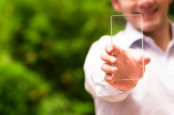 Bonito homem sorrindo enquanto ele segura futurista telefone inteligente transparente em sua mão — Fotografia de Stock