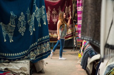 Yürüyüş ve and geleneksel giyim bakarak ve kamera, renkli kumaşlar arka plan için poz güzel bir gülümseyen genç kadının yakın çekim