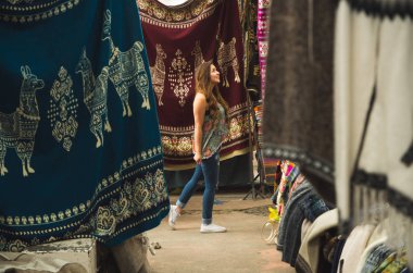 Yürüyüş ve and geleneksel giyim bakarak ve kamera, renkli kumaşlar arka plan için poz güzel bir gülümseyen genç kadının yakın çekim