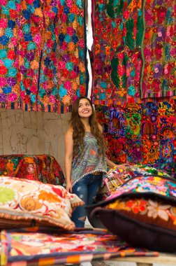 Güzel bir gülümseyen genç kadının and geleneksel giyim ve kamera, renkli kumaşlar arka plan için poz dokunmadan yakın çekim