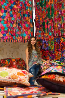Güzel bir gülümseyen genç kadının and geleneksel giyim ve kamera, renkli kumaşlar arka plan için poz dokunmadan yakın çekim