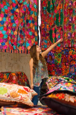 Güzel bir gülümseyen genç kadının and geleneksel giyim ve kamera, renkli kumaşlar arka plan için poz dokunmadan yakın çekim