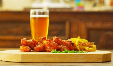 Ketçap, hardal ve bir bardak bira ahşap tahta üzerinde lezzetli ızgara tavuk kanadı