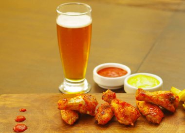 Ketçap, hardal ve bir bardak bira ahşap tahta üzerinde lezzetli ızgara tavuk kanadı