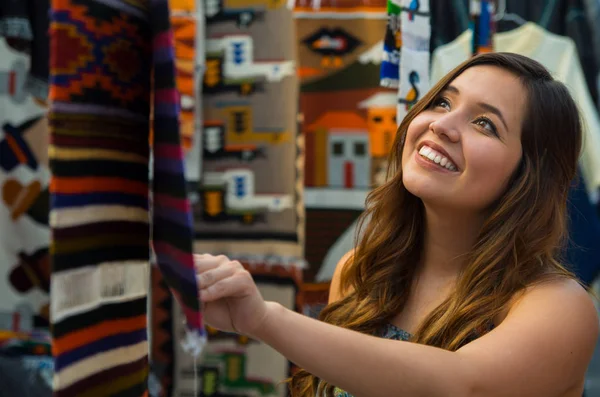 Nahaufnahme einer jungen Frau, die einen andinen Rucksack berührt, traditionelle Kleidung, Textilgarn und von Hand in Wolle gewoben, farbenfroher Stoffhintergrund — Stockfoto