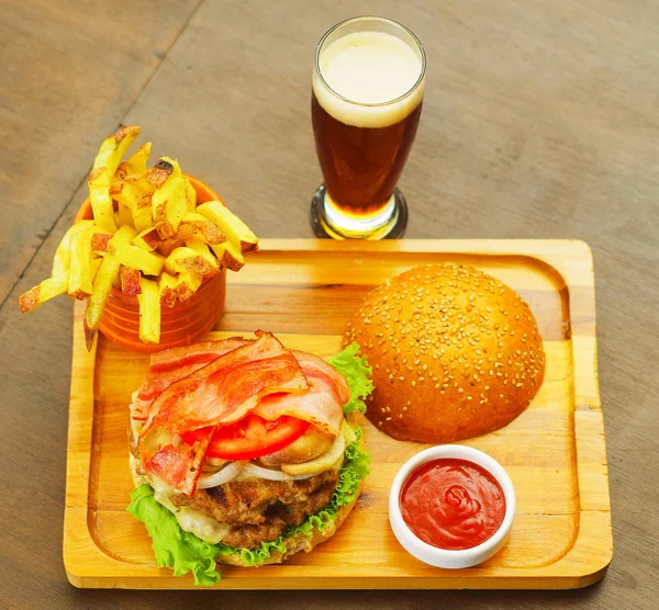 Closeup up of a delicious hamburger with beef, onion, tomato, lettuce and cheese on wooden board, above view