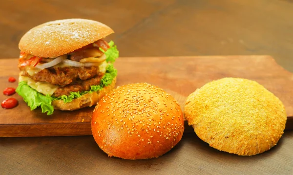 Deliciosa hamburguesa completa con dos piezas de pan al lado de la hamburguesa sobre tabla de madera —  Fotos de Stock